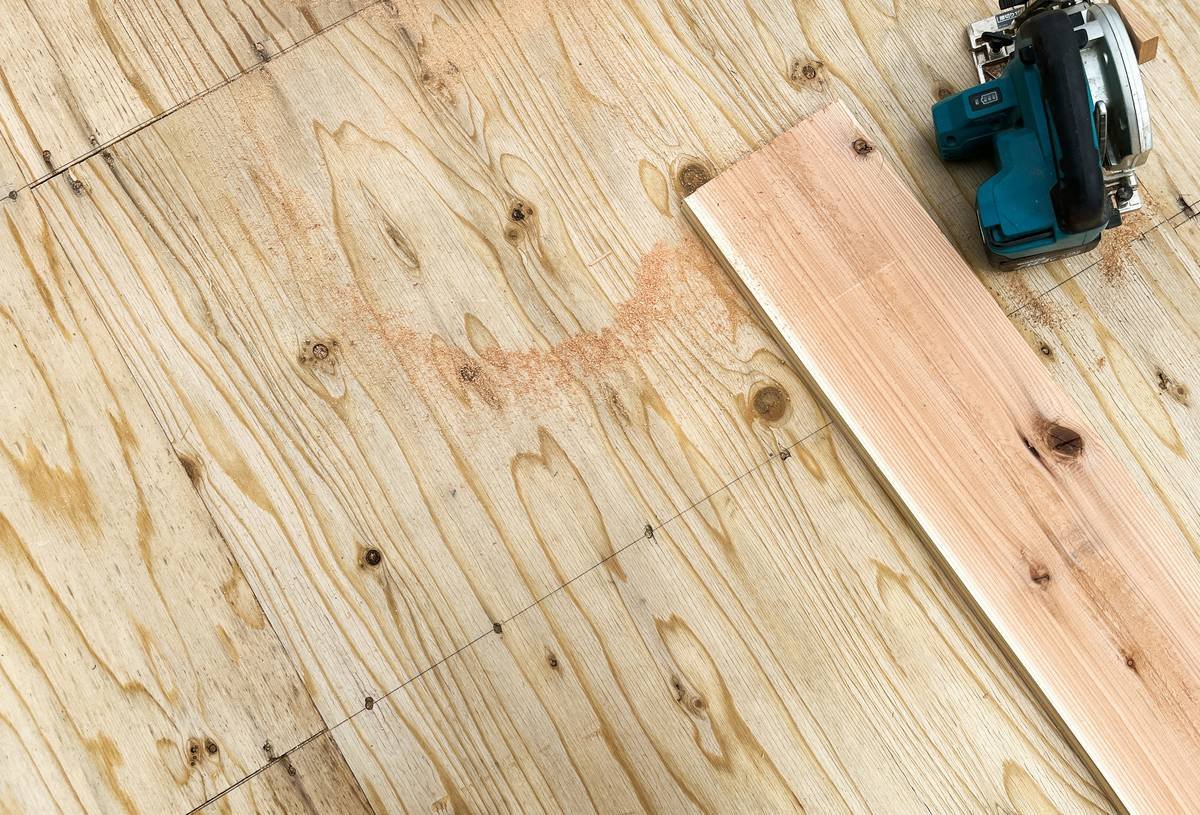 DIYer installing self adhesive vinyl flooring roll with J-roller on clean subfloor